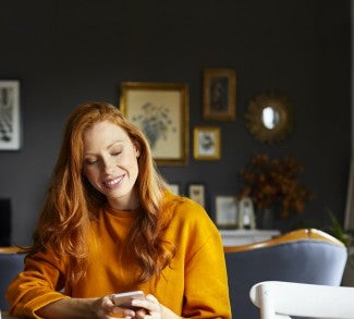 Woman sitting on couch in room on mobile phone
